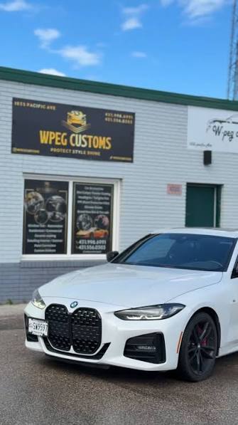 White BMW 4 Series with professional window tint parked outside WPEG Customs window tint shop in Winnipeg during summer